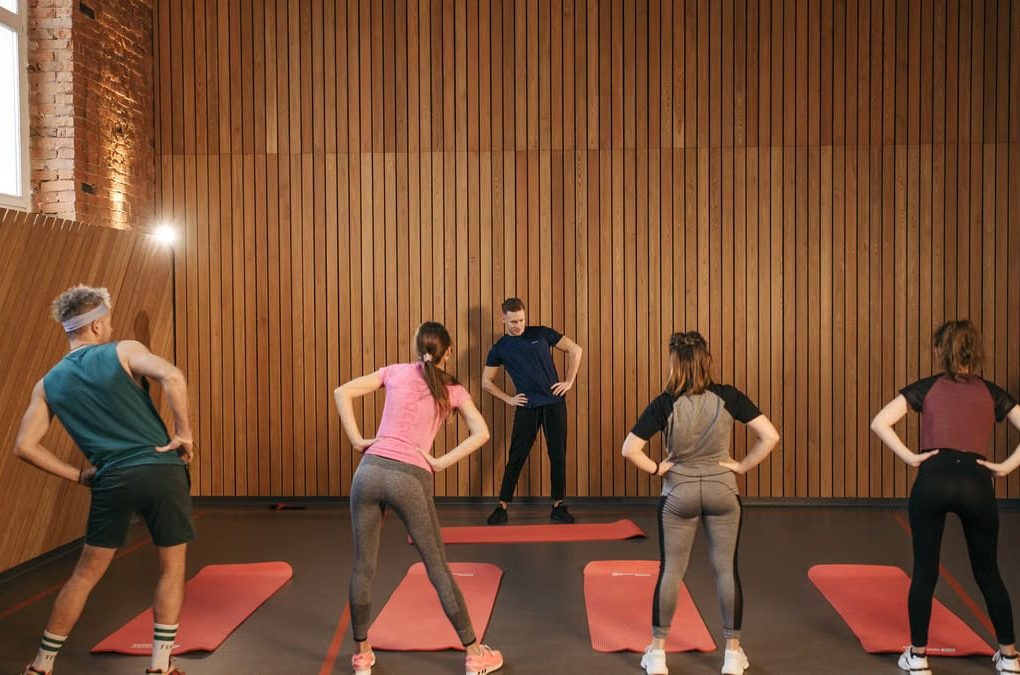 People stretching on yoga mats during a fitness class indoors.