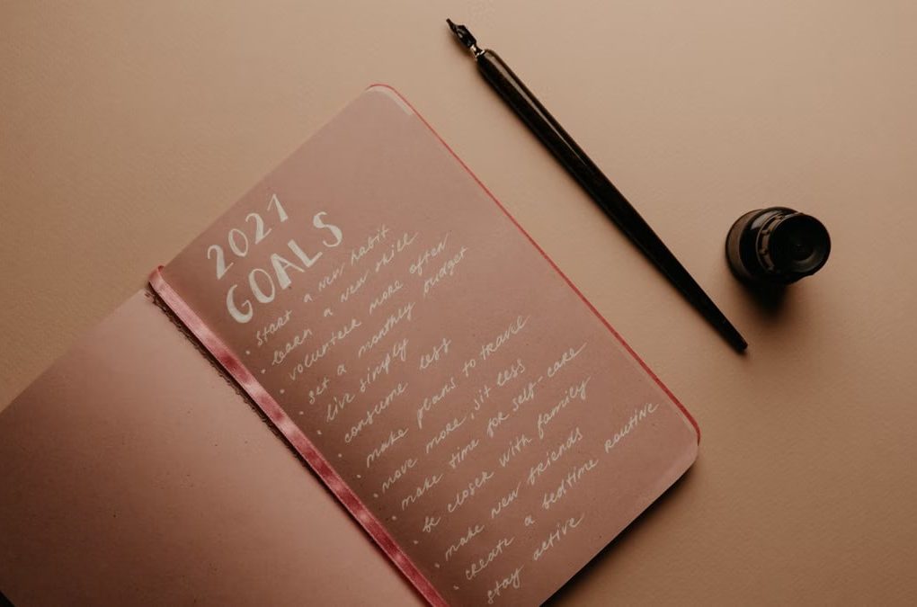 A notebook with '2021 Goals' written in calligraphy, featuring a pen and ink bottle.