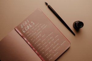A notebook with '2021 Goals' written in calligraphy, featuring a pen and ink bottle.