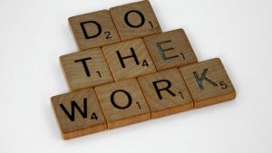 Creative arrangement of Scrabble tiles spelling 'Do the Work' on a white background.